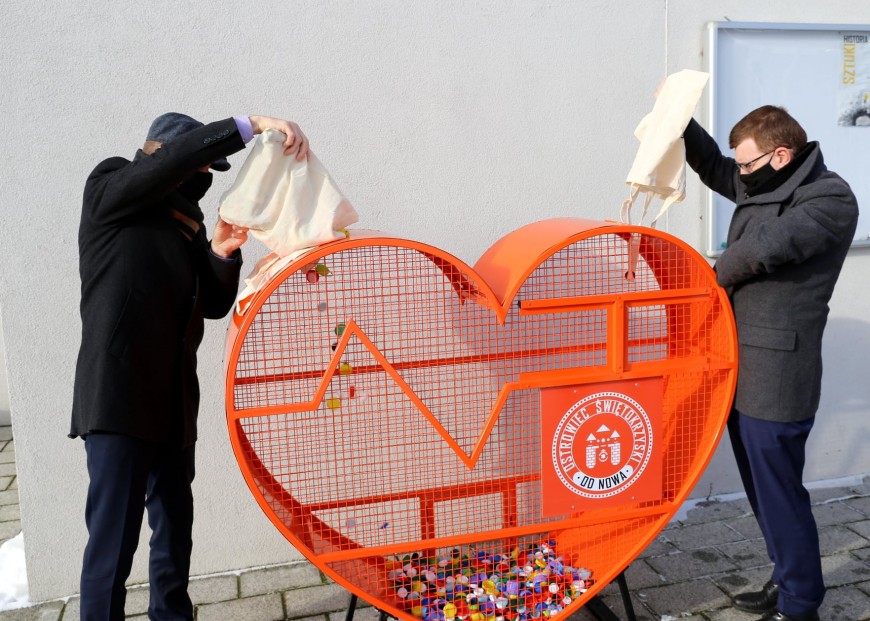 Prezydent miasta Jarosław Górczyński oraz wiceprezydent miasta Piotr Dasios wsypują plastikowe nakrętki do kontenera w kształcie serca